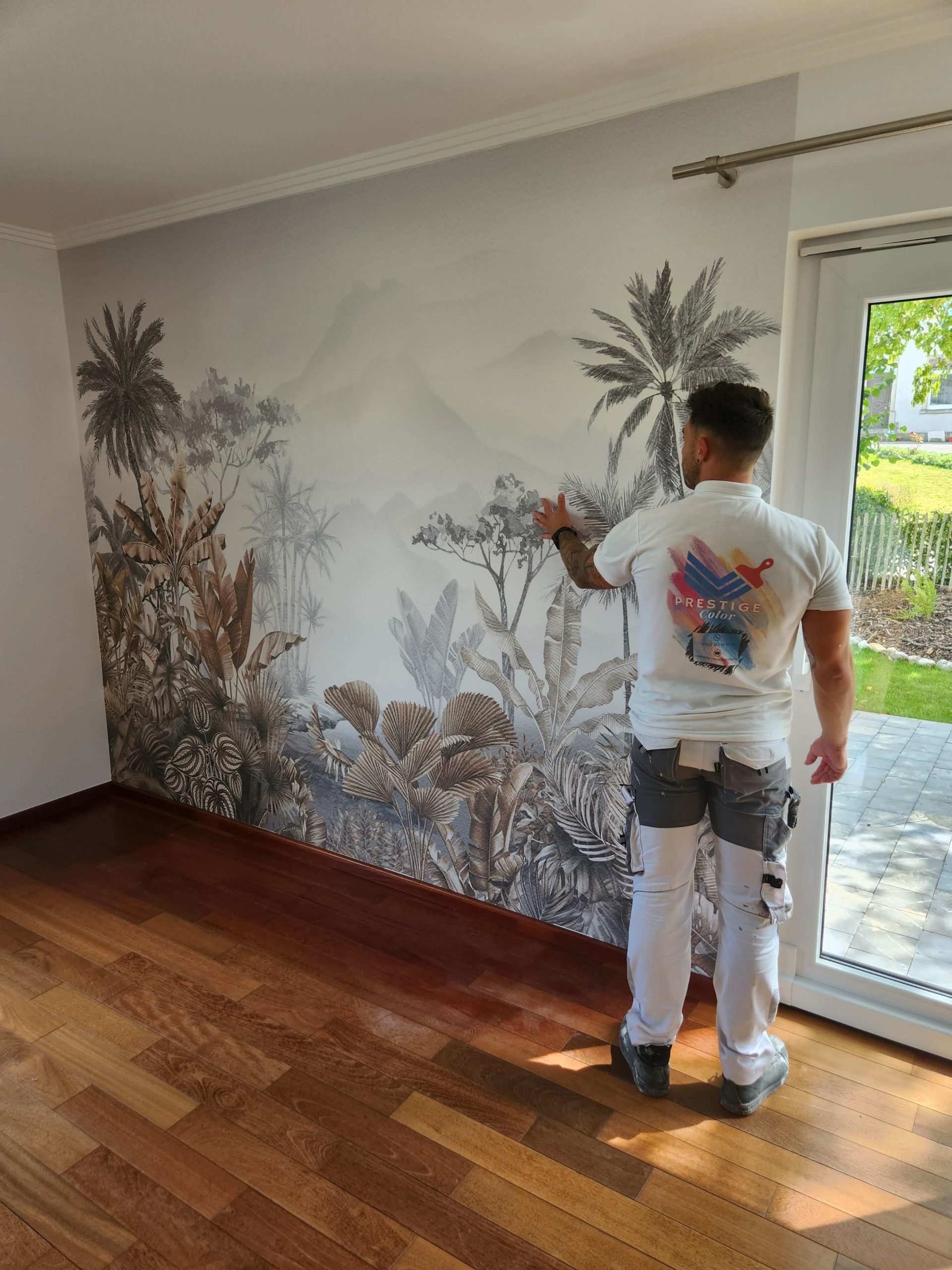 tapisserie Messancy Peintre PrestigeColor contrôlant la pose d'une tapisserie sur un mur